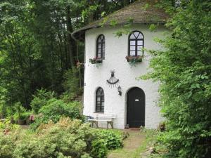 - un bâtiment blanc avec une porte et des fenêtres noires dans l'établissement Cosy Holiday Home in Strotzb sch with Sauna, à Strotzbüsch