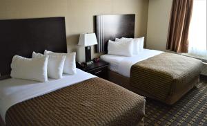 um quarto de hotel com duas camas e uma janela em Sigma Inn & Suites em Melville