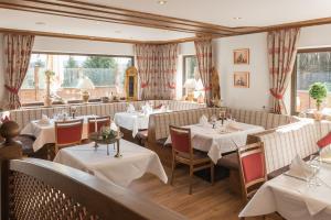 ein Restaurant mit weißen Tischen und Stühlen und Fenstern in der Unterkunft Landhotel Windlicht in Krombach