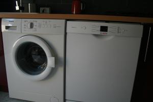 - un lave-linge et un sèche-linge blancs sous un comptoir dans l'établissement Gîte La Lexovienne Lisieux Centre, à Lisieux