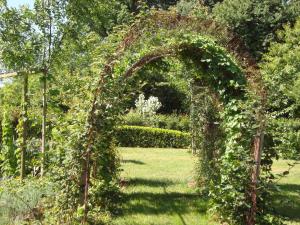 einen mit Efeu bedeckten Bogen in einem Garten in der Unterkunft Rustic holiday home with garden in Normandy in Gouvets