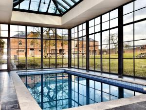 uma piscina interior com janelas grandes e uma piscina grande em Luxurious Mansion with indoor pool and Sauna em Mesnil-Saint-Blaise