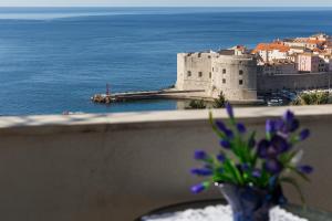 a vase with purple flowers on a ledge with a castle at Apartments Dalmatin in Dubrovnik