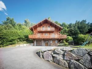 a log house with a balcony and a playground at Beautiful chalet with sauna and views of Vosges in Anould