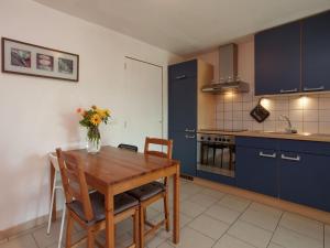 cocina con mesa de madera y armarios azules en Cozy Apartment in Stoumont with Private Terrace, en Stoumont