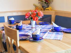 a table with blue dishes and a vase of flowers at Apartment in Reitersau near the ski area in Steingaden