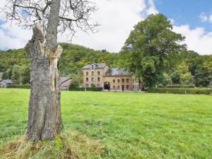 ein Baum auf einem Feld vor einem Gebäude in der Unterkunft A large family house in Stavelot