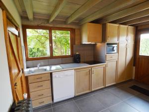 cocina con armarios de madera, fregadero y ventana en With a broad view over the hilly landscape, en Flobecq