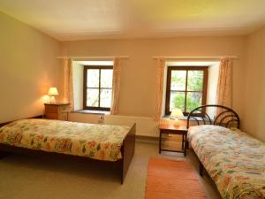 1 dormitorio con 2 camas y 2 ventanas en This plain house is very suitable for groups, en Ferrières