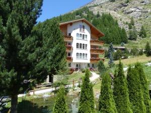 ein Hotel in den Bergen mit Bäumen im Vordergrund in der Unterkunft Haus Rubin in Saas-Almagell