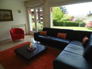 ein Wohnzimmer mit einem schwarzen Sofa und einem roten Stuhl in der Unterkunft Belvilla by OYO Varese Quattro in Comerio