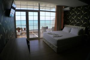 a bedroom with a bed and a view of the ocean at Espana aparthotel in Durrës