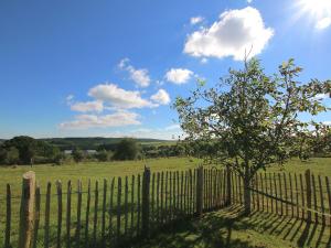 een hek met een boom in een veld bij Ecologically renovated former farmhouse in Wellin