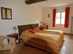 a bedroom with two beds and a chair and a window at Pleasant holiday home with garden in Isigny-le-Buat
