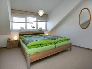 1 dormitorio con cama con almohadas verdes y espejo en Apartment in Dietmannsried near the forest, en Dietmannsried