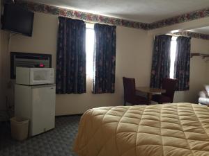 a hotel room with a bed and a television and a table at Baxter Inn 4 Less in Baxter Springs