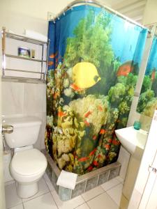 a bathroom with an aquarium shower curtain with a toilet at Beach Studio 6 in Ocho Rios