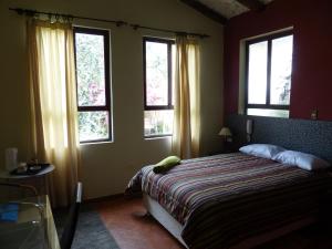 a bedroom with a bed in a room with windows at Casa de Campo Santa Rosa in Cajamarca