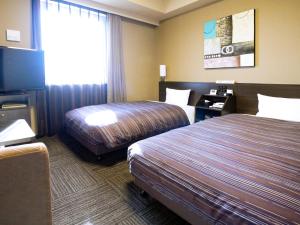 a hotel room with two beds and a flat screen tv at Hotel Route-inn Ebina Ekimae in Ebina