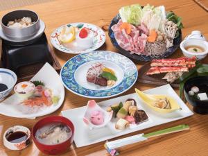 una mesa de madera con platos de comida. en Tokiwaso en Miyakonojō