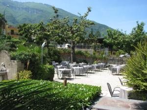restauracja ze stołami i krzesłami oraz górami w tle w obiekcie Hotel Parco w mieście Castellammare di Stabia