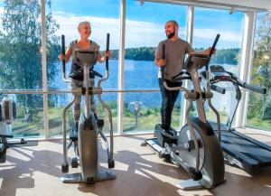 un homme et une femme faisant de l'exercice sur des vélos d'exercice dans une salle de sport dans l'établissement Spa Hostel Kunnonpaikka, à Kuopio