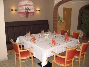 mesa de comedor con mantel y sillas blancas en Parkhotel Phoenix Garni, en Hage
