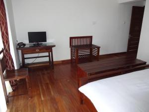 a bedroom with a bed and a desk with a television at Irinjalakuda House in Ooty