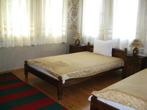 a bedroom with two beds and windows with curtains at Elefterova kashta in Arbanasi