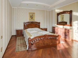 a bedroom with a large wooden bed and a mirror at Ghostinitsa "Lina" in Petropavlovsk