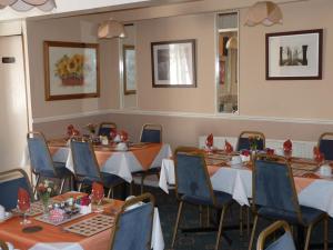 uma sala de jantar com mesas e cadeiras e um espelho em The Avon em Blackpool