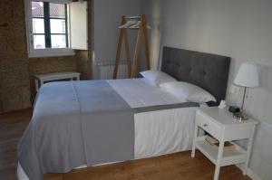サンティアゴ・デ・コンポステーラにあるA Casiñaのベッドルーム1室(大型ベッド1台、白いナイトスタンド付)
