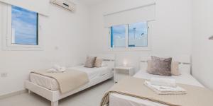 two beds in a white room with windows at Sea View Villa Paralimni in Paralimni