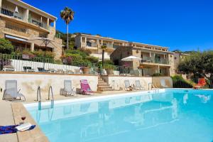 a swimming pool with two chairs and a building at Residence Roc E Mare Cargèse in Cargèse