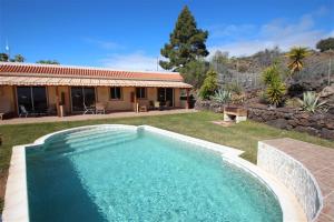a swimming pool in a yard next to a house at Apartment Colibri Finca Montimar in Los Carrizales