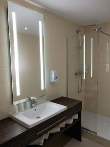 a bathroom with a sink and a shower and a mirror at Kyriad Poitiers Jules Verne Site du Futuroscope in Chasseneuil-du-Poitou