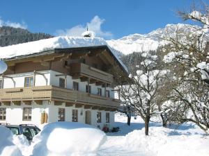 ein schneebedecktes Gebäude vor einem Berg in der Unterkunft Herzoghof in Leogang