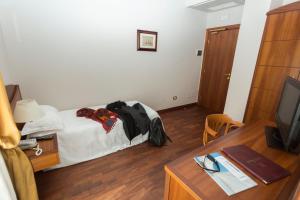 a hotel room with a bed and a desk with a television at Hotel Cavaliere in Noci