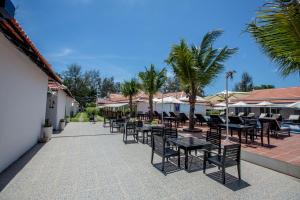 a patio with tables and chairs and palm trees at Good Time Resort in Sihanoukville