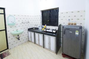 a bathroom with a sink and a refrigerator in it at Brittos Homestay in Mandrem +30 photos