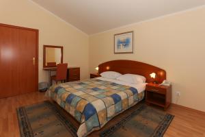 1 dormitorio con 1 cama con cabecero de madera en Apartments and Rooms Astoria, en Trogir