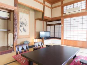 a dining room with a table and chairs and a tv at 神水館 都心から一番近い秘湯八塩温泉 in Fujioka