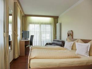 ein Hotelzimmer mit einem großen Bett und einem Schreibtisch in der Unterkunft Rebstock Kappelwindeck in Bühl