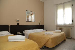 a room with two beds with towels on them at Hotel Villa Dina in Rimini