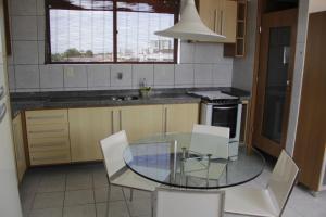 a kitchen with a glass table and white chairs at Portugal Flat in João Pessoa