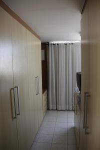 a kitchen with white cabinets and a white tile floor at Portugal Flat in João Pessoa