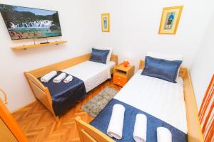 a bedroom with two beds and a tv on the wall at Holiday Home Obrov in Kaštela