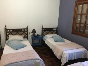 1 dormitorio con 2 camas y mesa con lámpara en Roma Hotel en Porto Alegre