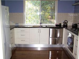 a kitchen with a sink, stove and a window at Koala Tree Motel in Port Macquarie