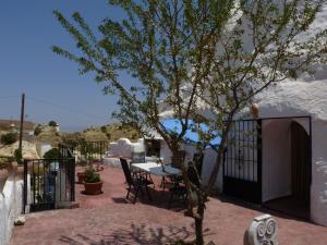 een patio met een tafel en stoelen en een boom bij Casa Cueva Guadix in Guadix